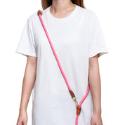 Person wearing a white shirt with a pink and brown strap over their shoulder on a white background